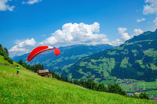 Paraglider preparing for flight over the green alpine meadows