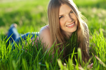 Naklejka na ściany i meble Beautiful woman are relaxing in a spring green field