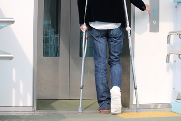 エレベーターのボタンを押す松葉杖の男性