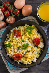 scrambled egg with grilled tomato in vintage iron pan from above