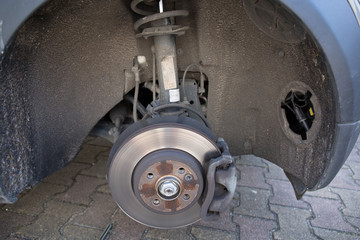 Front disc brake on car in process of new tire replacement