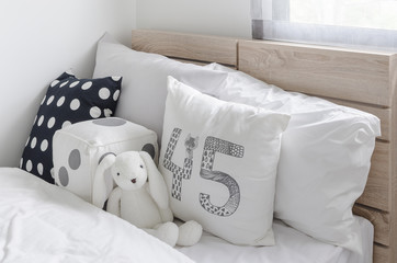 black and white pillows with doll on wooden bed in kid's bedroom