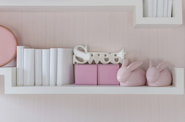 Fototapeta na wymiar Decorative shelf on pink wall with rabbits ceramic and word 
