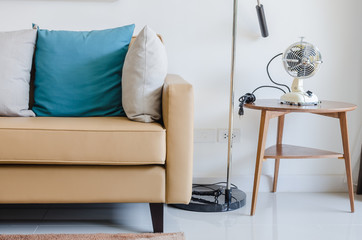 modern sofa with pillows and classical electric fan on wooden ro