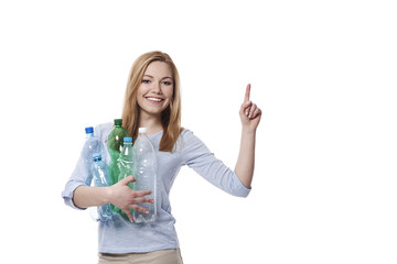 Woman with stack of plastic bottles pointing at copy space