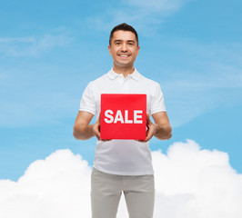 smiling man with red sale sigh over blue sky