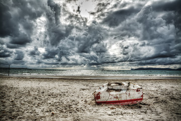 boat on the sand under a dramatic sky