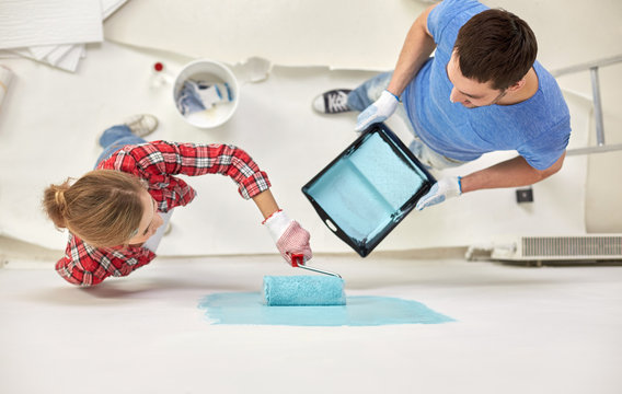 Couple With Paint Roller Painting Wall At Home