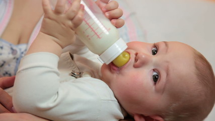 Cute baby boy drinking milk formula from a bottle