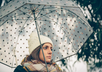 Young girl holding umbrella in an autumn rainy day