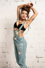 Young woman in tattoos standing with hands behind head