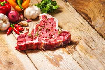 Close-up of fresh meat steak with spices on wooden background