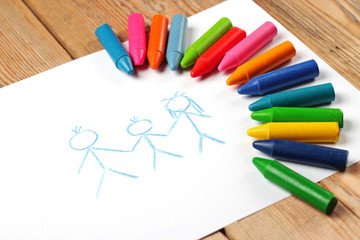 Obraz premium Oil pastel crayons lying on a paper with painted family
