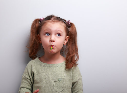 Funny Thinking Kid Girl Eating Lollipop And Looking Up