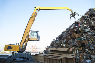 Large tracked excavator working a steel pile at a metal recycle