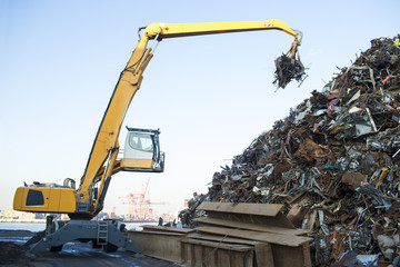 Large tracked excavator working a steel pile at a metal recycle