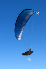 Paraglider flying over mountains in summer day