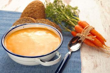 Soup with pumpkin and carrot on a blue tablecloth in country sty