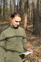 Mężczyzna z mapą i kompasem w lesie © nestonik