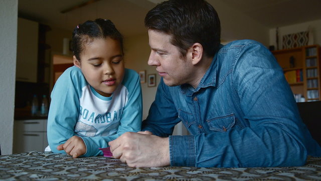 Happy dad explaining his daughter something at home