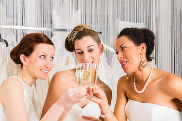 Brides drinking champagne in wedding shop