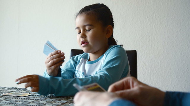 Happy young girl playing cards with her dad