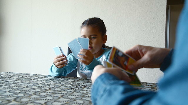 Happy young girl playing cards with her dad