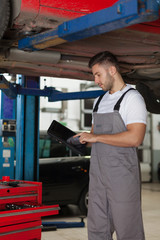 Fototapeta na wymiar Working on a Digital Tablet in Auto Repair Shop