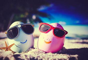Two easter eggs with sunglasses on ocean beach –retro style