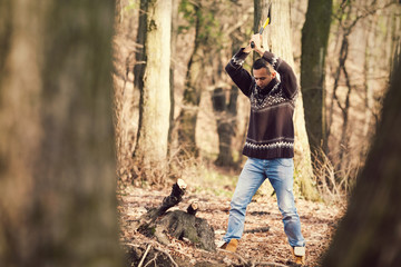 Young lumberman cutting the tree with an axe