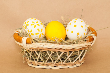 three easter colored eggs in basket with hay