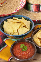 Mexican nachos with bowl of hot salsa traditional rug or blanket sombrero background Mexico food photo vertical