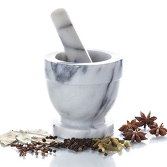 Marble mortar and pestle with assorted spices on white backgroun
