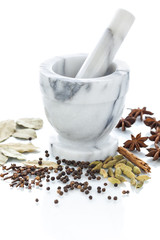 Marble mortar and pestle with assorted spices on white backgroun