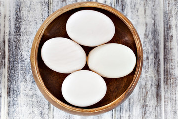 Duck eggs in brown wooden bowl