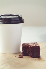 Take away coffee cup and chocolate brownie in muted tones
