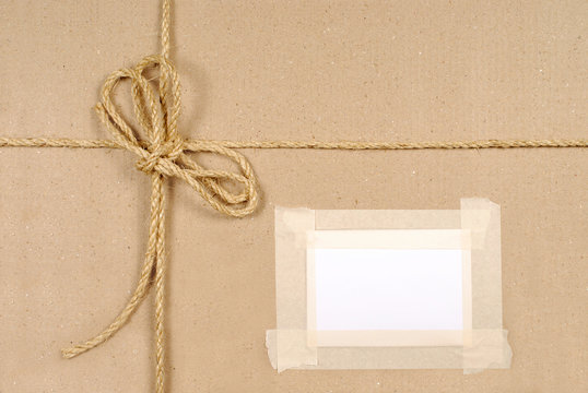 Brown paper package parcel background tied with string or rope and blank message or address label photo 