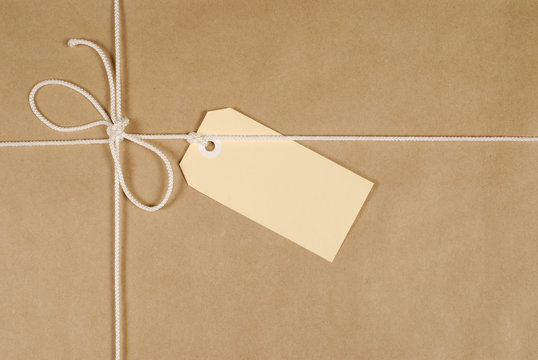 Brown paper package parcel background tied with string or rope and blank message tag or address label photo