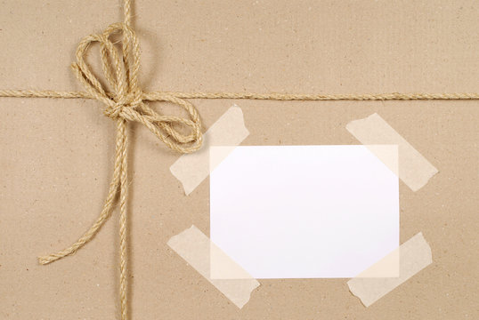 Brown paper package parcel background tied with string or rope and blank message tag or address label photo