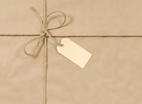Brown paper package parcel background tied with string or rope and blank message tag or address label photo