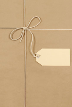 Brown paper package parcel background tied with string or rope and blank message tag or address label photo vertical