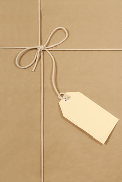 Brown paper package parcel background tied with string or rope and blank message tag or address label photo vertical