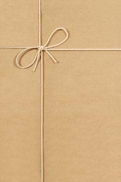 Brown paper package parcel background tied with string or rope photo vertical