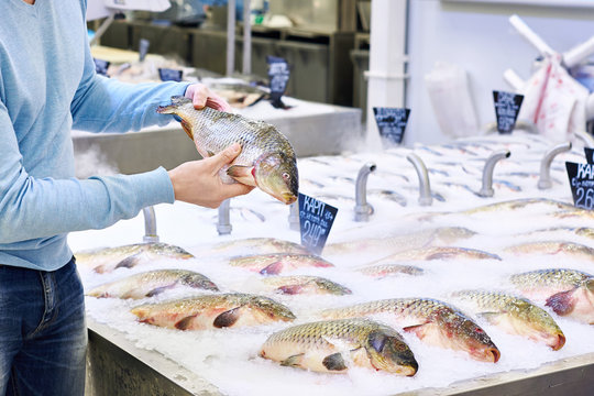 Man chooses carp fish in supermarket
