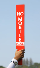 The no mobile sign was held up by volunteer in golf tournament.