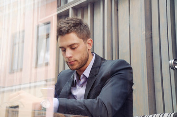 attractive businessman using device and drinking coffee in the c