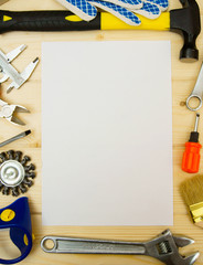 Paper for notes and set of working tools on wooden background.