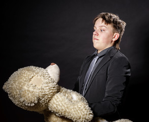 Teenage boy dressed in suit with his old toy - teddy-bear