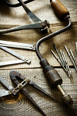 Old drill, compasses, ruler and drills on a wooden background.