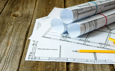Many drawings for building and pencils on old wooden background.